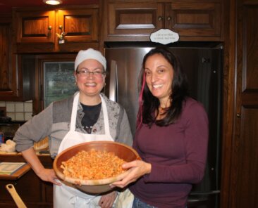 Ilia and Lisa hold the dish of tempeh bolognese pasta