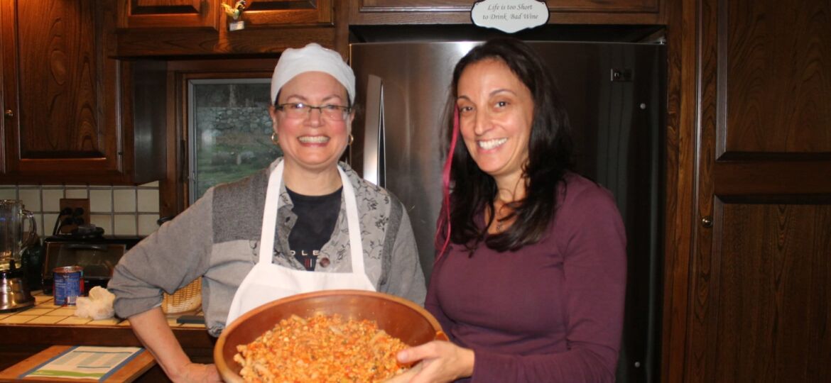 Ilia and Lisa hold the dish of tempeh bolognese pasta